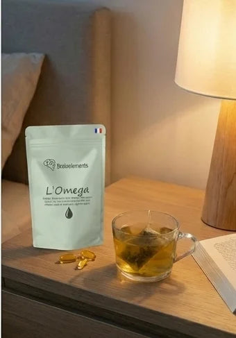 Sachet L'Omega posé sur une table de chevet à côté d'une infusion chaude et d'un livre, suggérant une prise relaxante avant de dormir.