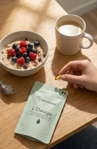 Prise d'une capsule d'Omega Brainelements lors d'un petit-déjeuner sain composé d'un bol de porridge aux baies et d'un café.